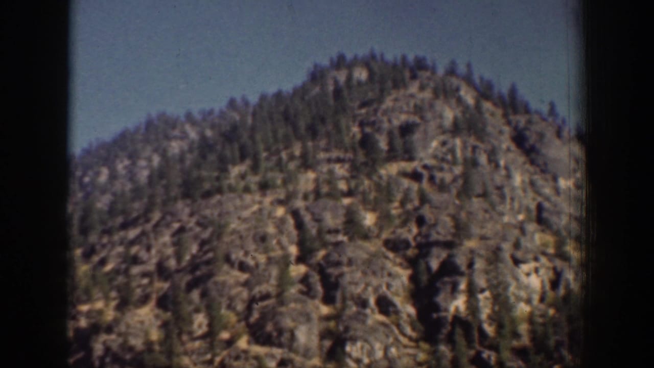 A rocky, tree-topped hillside near Chelan, Washington, seen in vintage 8mm home-movie color.