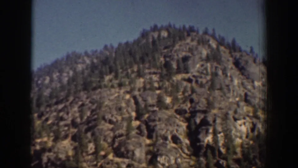 A rocky, tree-topped hillside near Chelan, Washington, seen in vintage 8mm home-movie color.