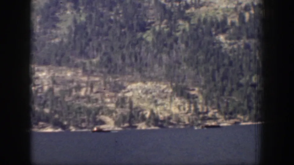 Chelan, Washington mountain lake scene with evergreen slopes, pale rock faces, and a small distant boat on the water.
