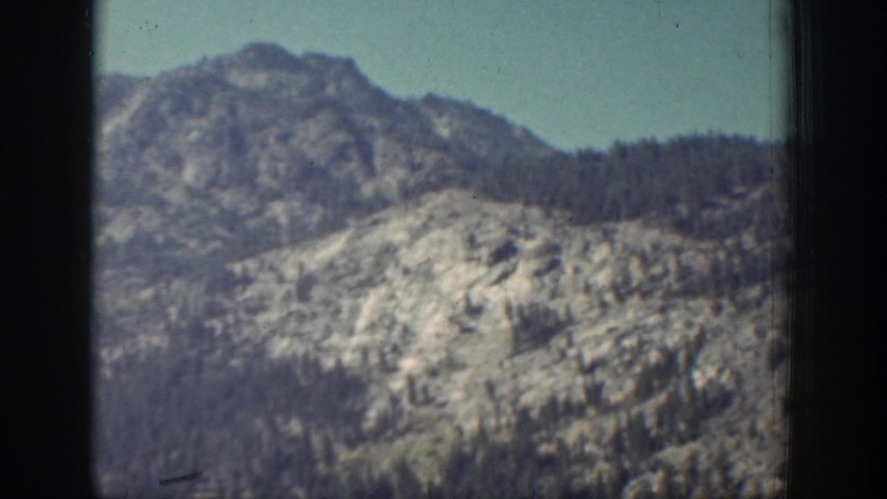Rocky mountain ridge with forested slopes beneath a pale sky.