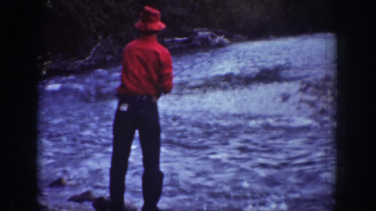 Rear view of the fisherman in red standing close to the fast-moving river in Chelan, Washington.