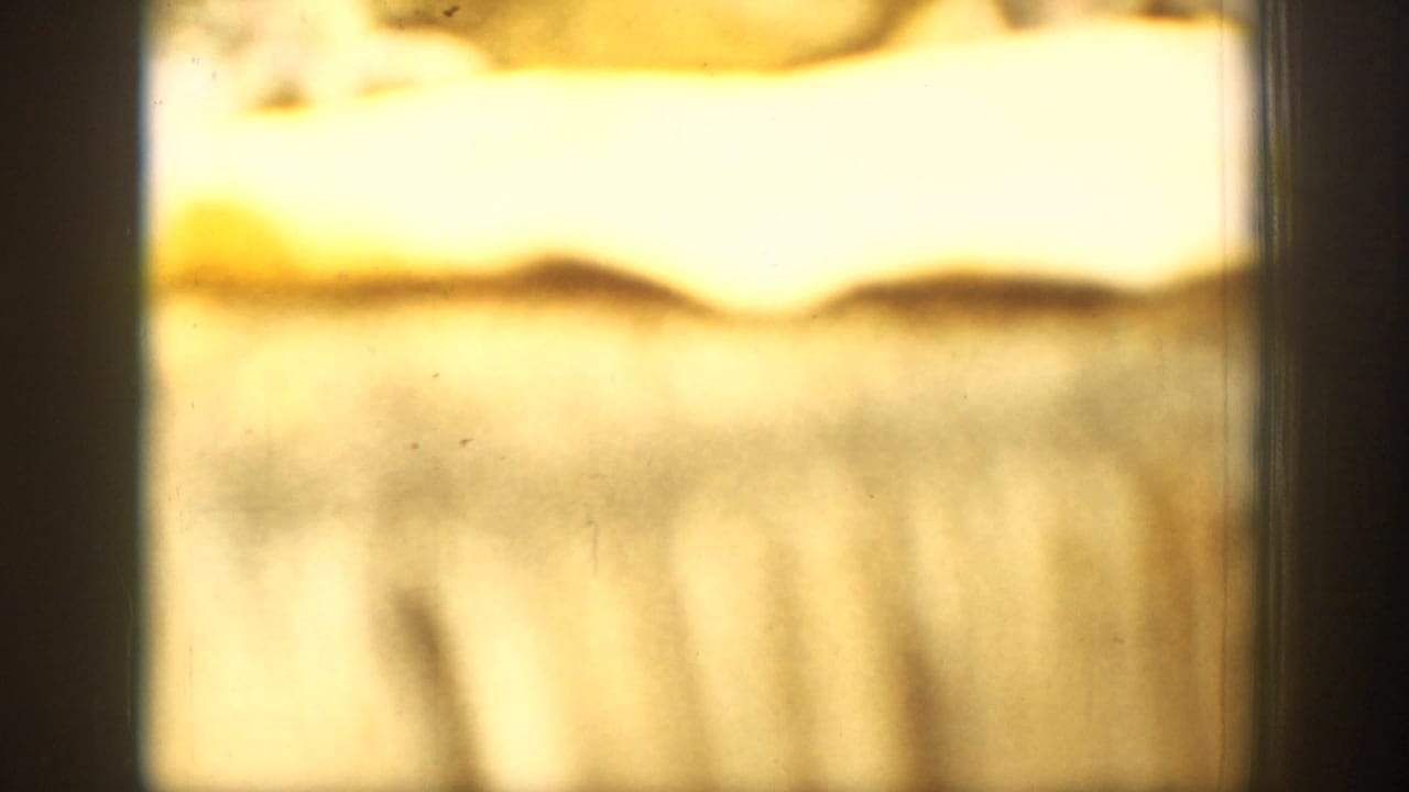 Overexposed 8mm home-movie frame from the Chelan sequence, with blurred warm-toned landscape shapes and visible film marks.