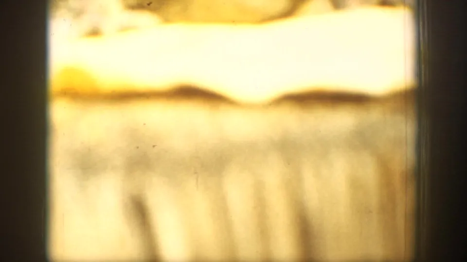 Overexposed 8mm home-movie frame from the Chelan sequence, with blurred warm-toned landscape shapes and visible film marks.