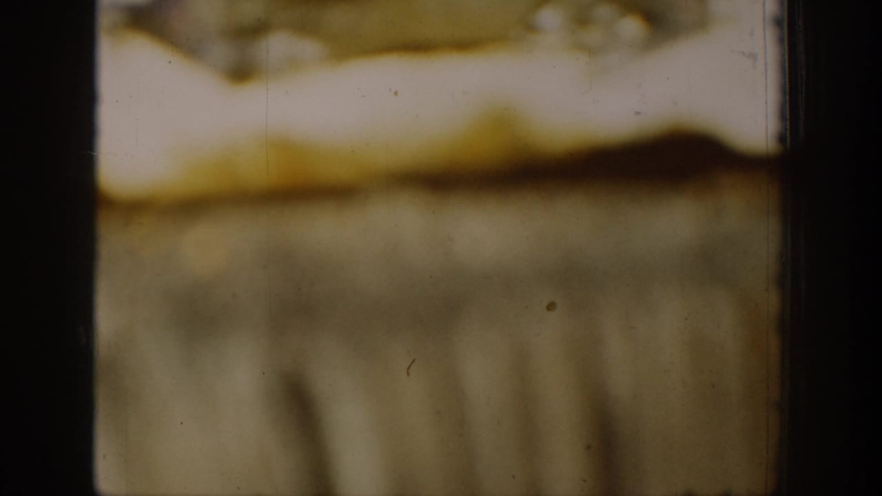 Soft, abstract film frame with browned emulsion, scratches, and black frame edges.