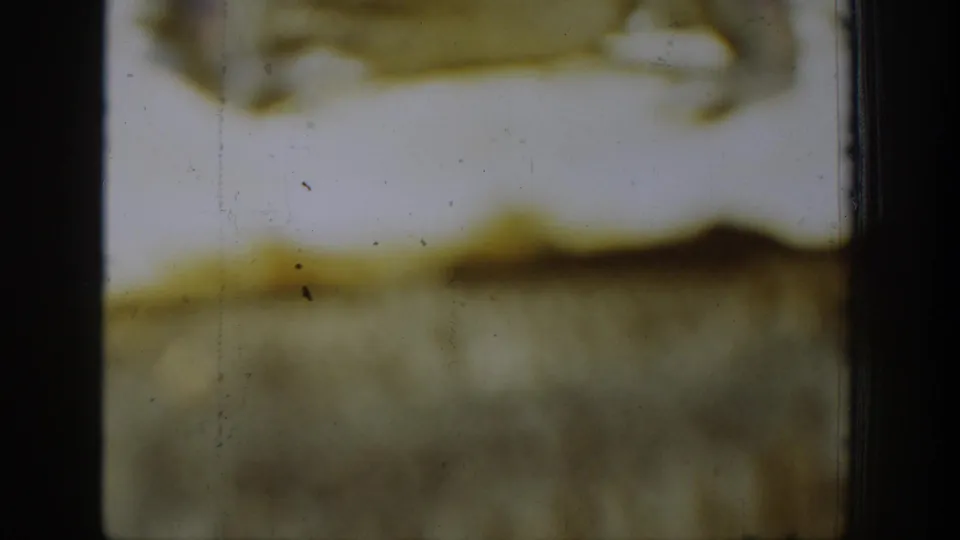 Final 1939 Chelan 8mm frame showing faded yellow emulsion, black frame edges, dust specks, scratches, and no identifiable people or property.