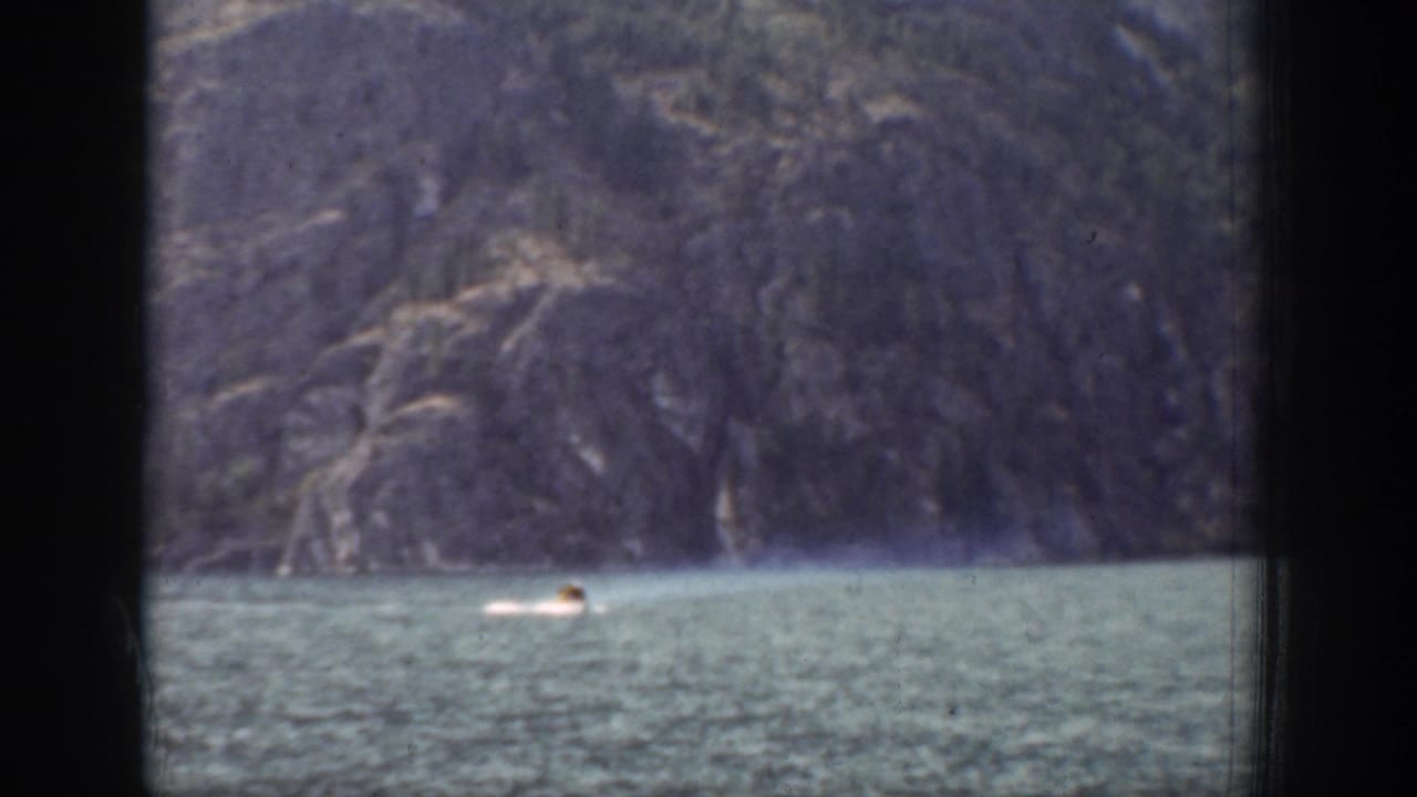 Distant swimmer in Chelan, Washington, seen on lake water against a rugged mountain backdrop in 1939 8mm footage.