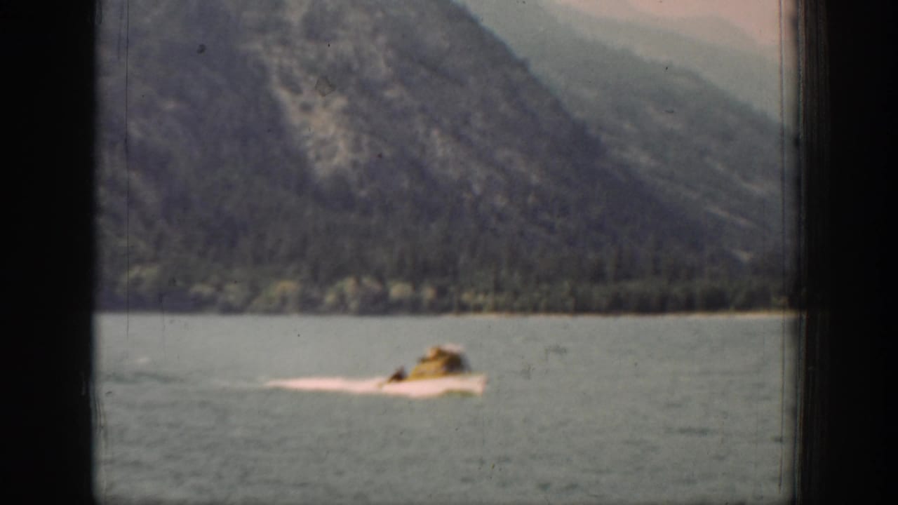 A small passenger boat travels across a mountain lake in supported Chelan, Washington home-movie footage from 1939.