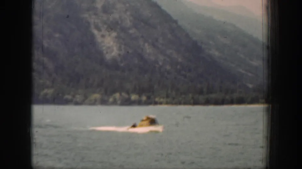 A small passenger boat travels across a mountain lake in supported Chelan, Washington home-movie footage from 1939.