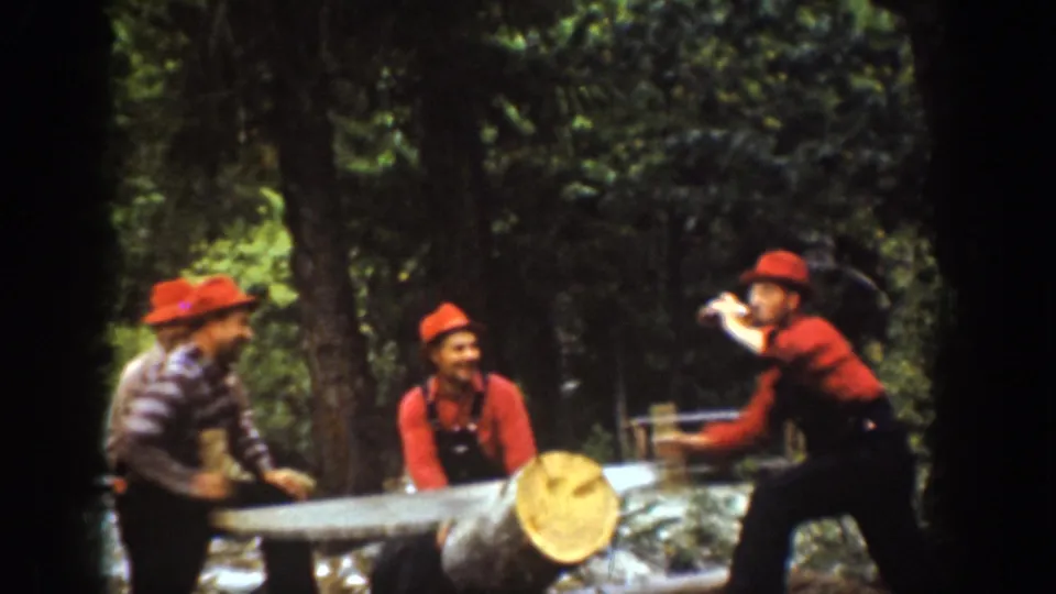 Chelan, Washington 1939 home-movie frame of four men in lumberjack-style clothing around a large log with a crosscut saw.
