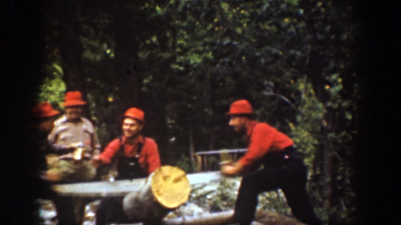1939 Chelan, Washington home-movie frame showing four adult men in red hats around a large log in the forest as one prepares to saw.