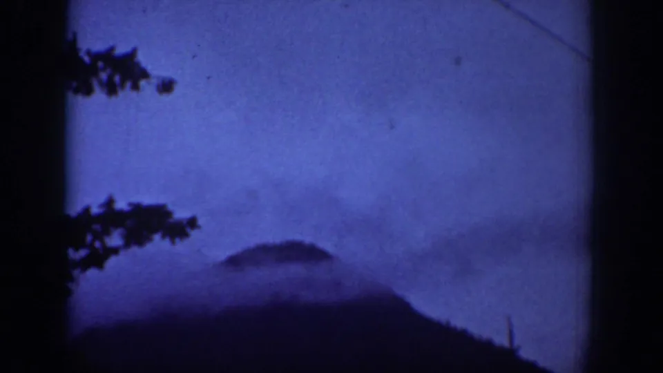 1939 Chelan-area 8mm frame showing a dark mountain shape, blue sky or haze, tree branches, and a diagonal utility line.