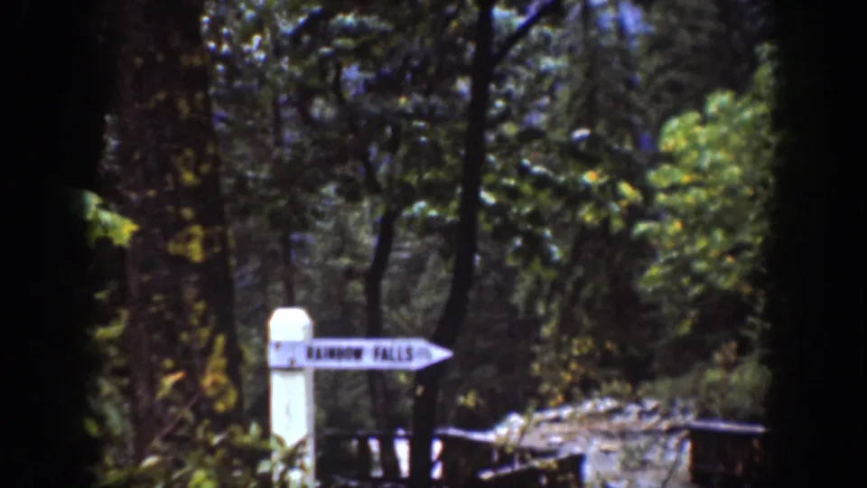 Closer view of the Rainbow Falls direction sign in a forested Chelan-area travel scene from the 1939 8mm clip.