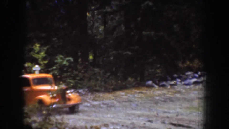Orange 1930s-era vehicle on a gravel forest pull-off in the Chelan, Washington home-movie sequence.