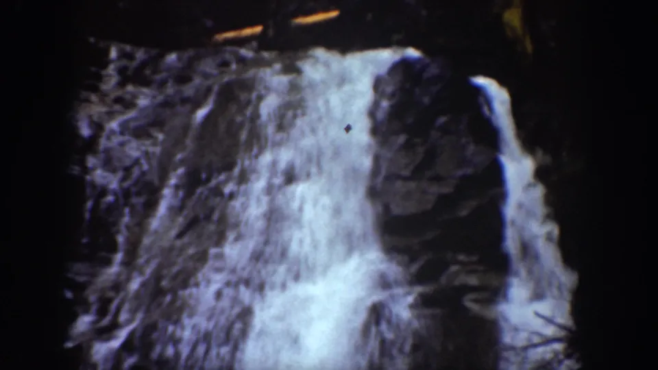 1939 Chelan, Washington home-movie frame showing a close view of water cascading over a rocky cliff face.