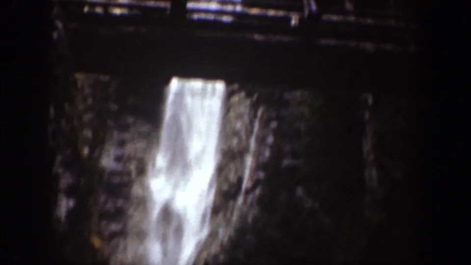 Soft 8mm frame of a waterfall plunging below a dark railing or bridge in Chelan, Washington.