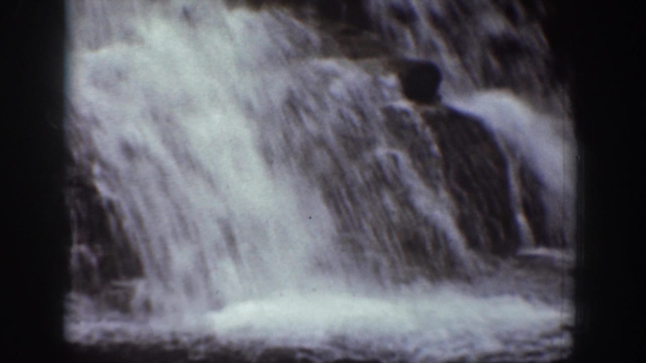 Close view of fast water cascading over rocks in a dark-framed 8mm shot.