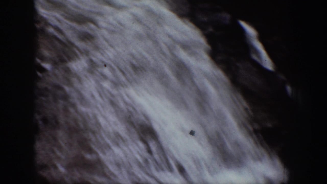 Diagonal close-up of white waterfall flow against dark rock.