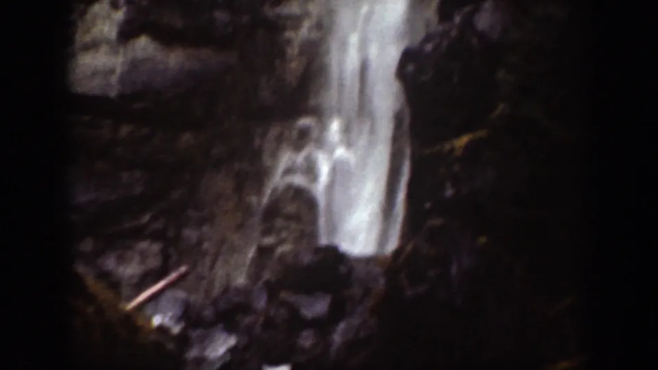 1939 Chelan, Washington frame with a close, soft-focus view of white water falling over dark rock ledges.