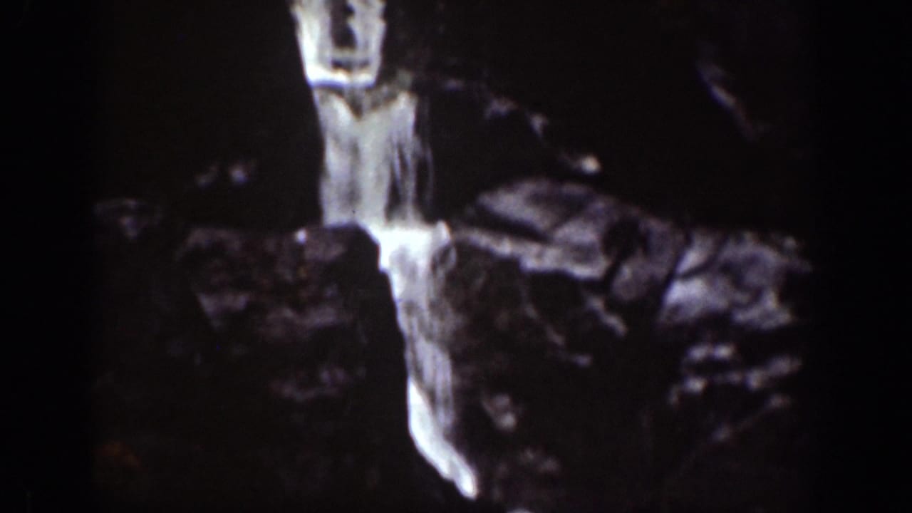 Vintage 8mm frame from the Chelan area showing a narrow waterfall dropping through rugged rock.