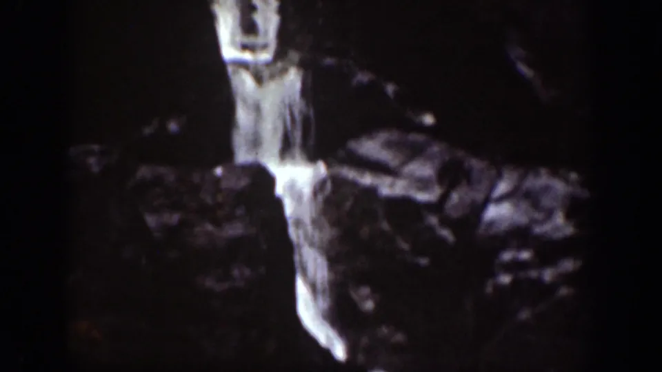 Vintage 8mm frame from the Chelan area showing a narrow waterfall dropping through rugged rock.