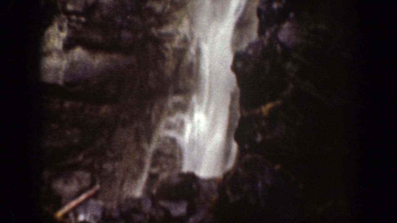 1939 Chelan-area frame showing bright falling water against steep dark rock and scattered branches.