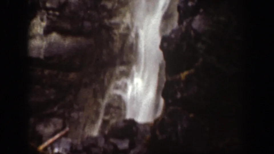 1939 Chelan-area frame showing bright falling water against steep dark rock and scattered branches.