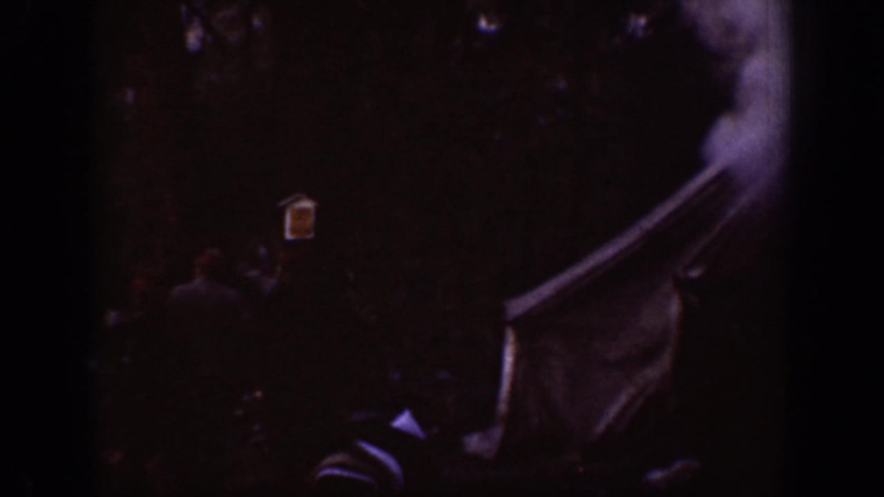 Chelan 1939 frame with smoke or haze near the tent structure, seen through heavy grain and low light.