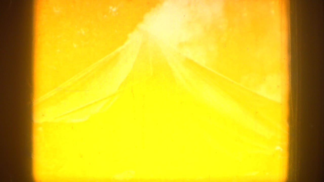 Final Chelan campsite frame dominated by yellow-orange fire glow, with a faint tent outline still visible.
