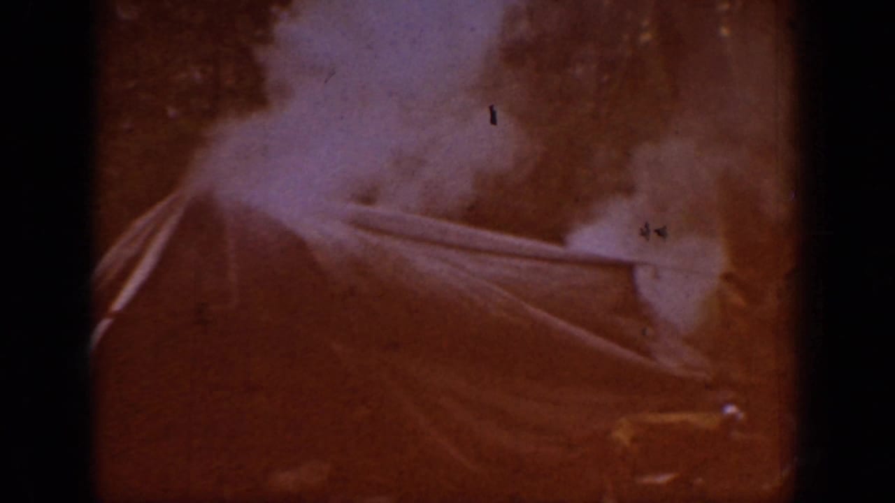 Opening frame from a 1939 8mm home movie reel dominated by an orange-red light leak; faint structural or foliage shapes just discernible through the overexposure.