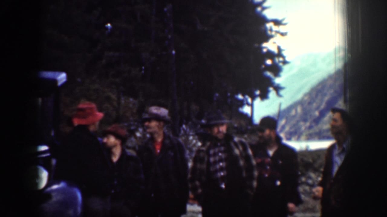 Five or six adults gathered on a conifer-lined dirt path near Lake Chelan, Washington, circa 1939; a figure in a red hat stands at left.