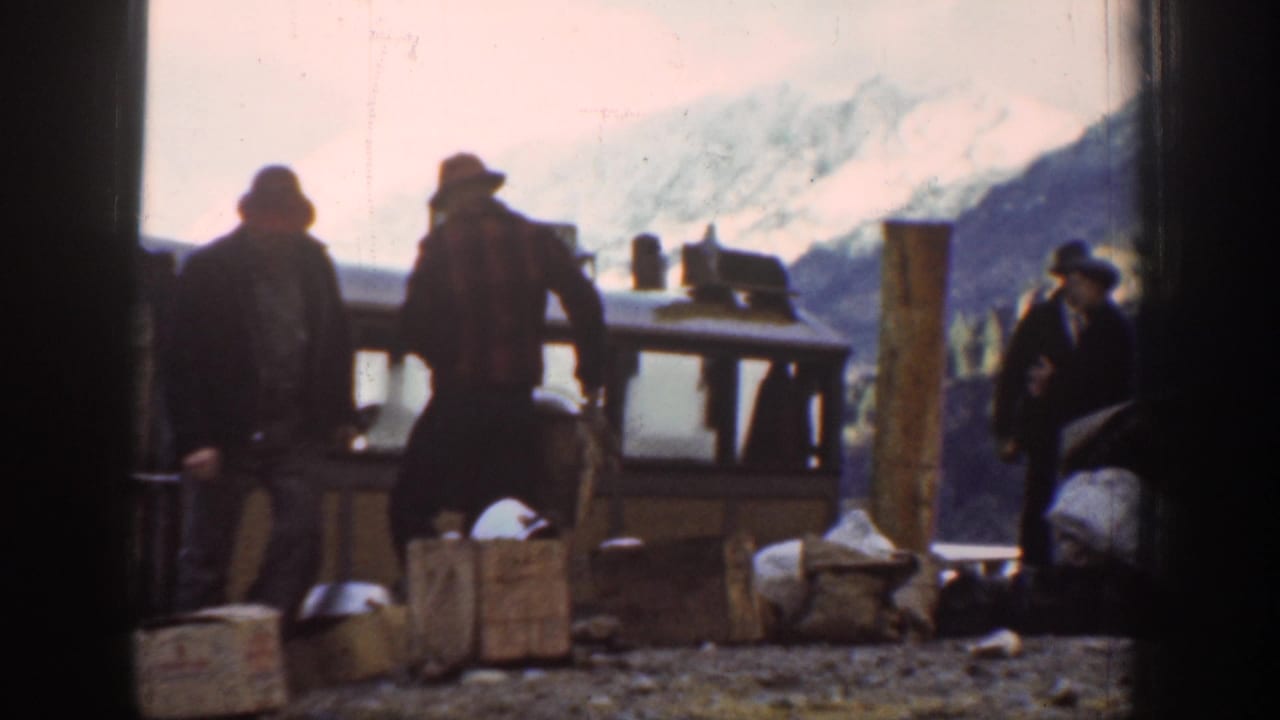 Several men in late-1930s work attire load wooden crates at an outdoor mountain-area depot, possibly near Chelan, Washington, circa 1939.