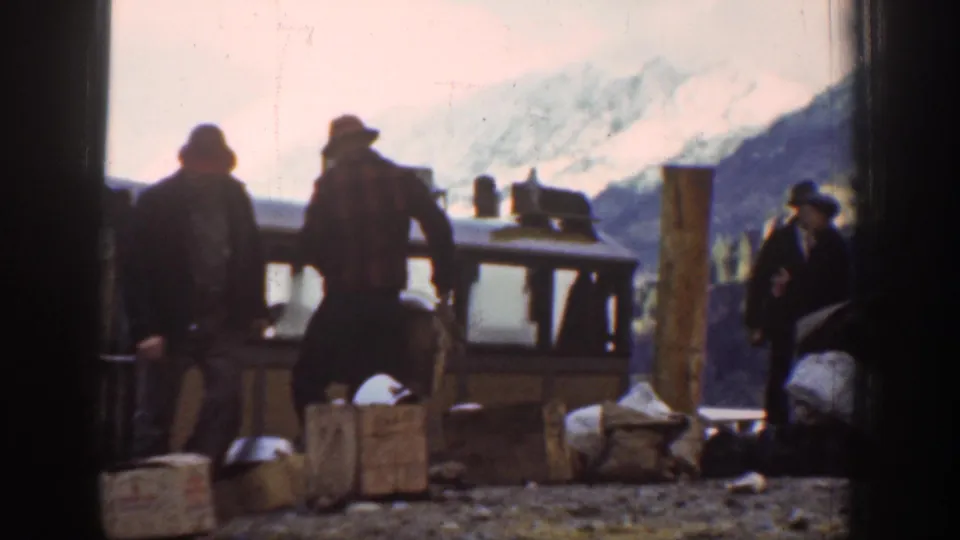 Several men in late-1930s work attire load wooden crates at an outdoor mountain-area depot, possibly near Chelan, Washington, circa 1939.