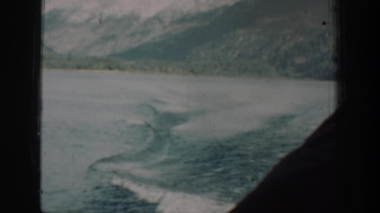 8mm footage from a 1939 Lake Chelan steamer journey showing the vessel's wake and distant forested mountains through a cabin porthole.