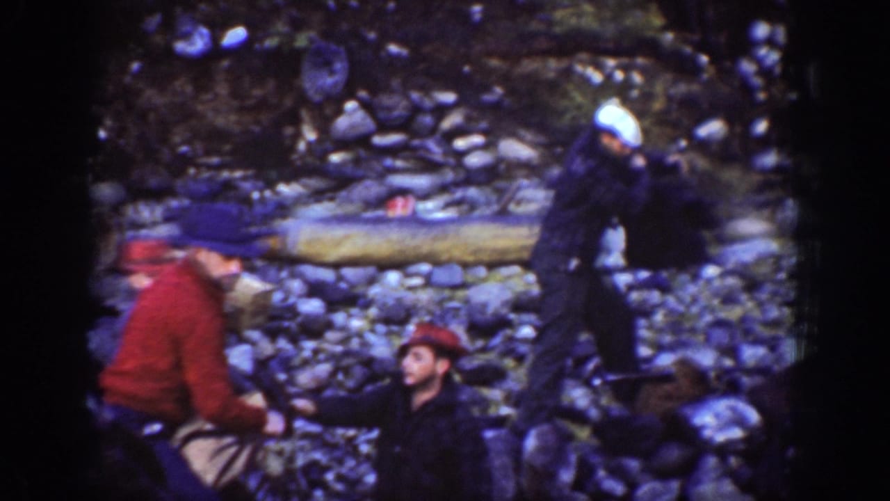 Three male workers in period work coats handle material in a rocky riverbed, likely Chelan area, Washington, circa 1939