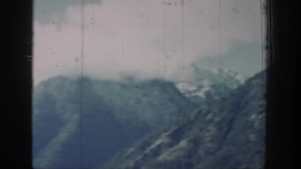 8mm color frame circa 1939 showing a steep mountain ridge across Lake Chelan, Washington, with an overcast sky and faded early color film stock.