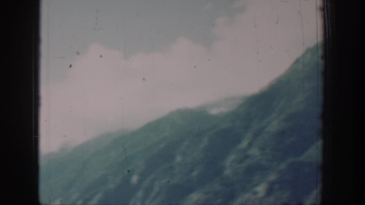 8mm color frame circa 1939 showing a mountain slope above a lake shoreline in the Chelan, Washington area with a muted, faded color palette.