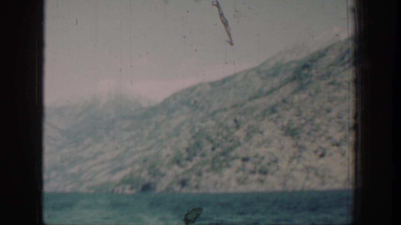 8mm color frame circa 1939 showing a mountain ridge above Lake Chelan, Washington; a diagonal film scratch artifact is visible in the upper right of the frame.