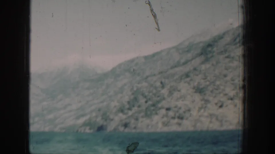 8mm color frame circa 1939 showing a mountain ridge above Lake Chelan, Washington; a diagonal film scratch artifact is visible in the upper right of the frame.