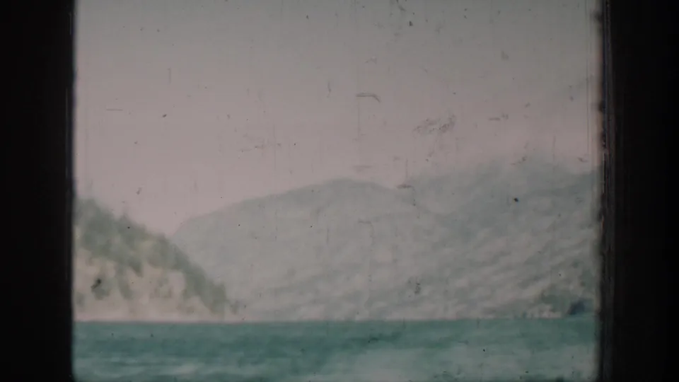 Wide mountain and lake view framed by a window edge, likely near Chelan, Washington, circa 1939, 8mm color film with teal cast.