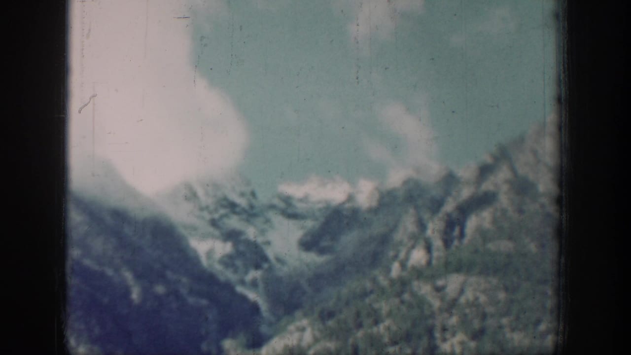 Close view of snow-capped peaks above dense forest, consistent with the mountains near Chelan, Washington, circa 1939, 8mm color film.