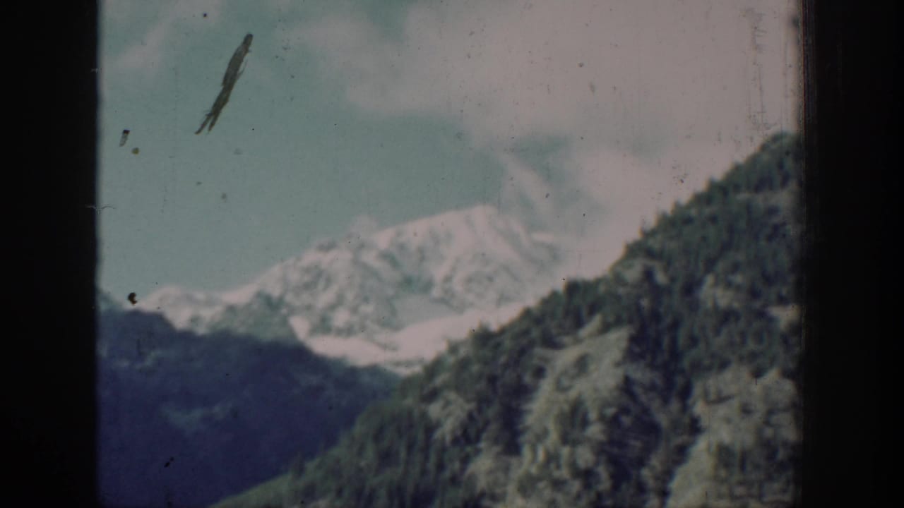 Mountain and forested slopes with a dark film scratch artifact across the frame, likely near Chelan, Washington, circa 1939, 8mm color film.