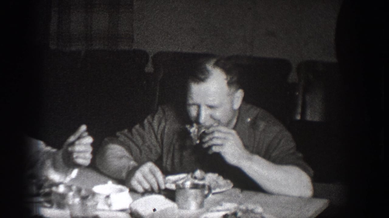 Man eating at an informal dinner gathering, Chelan, Washington, circa 1939; plates and food on the table; deep 8mm vignetting typical of this era and format.