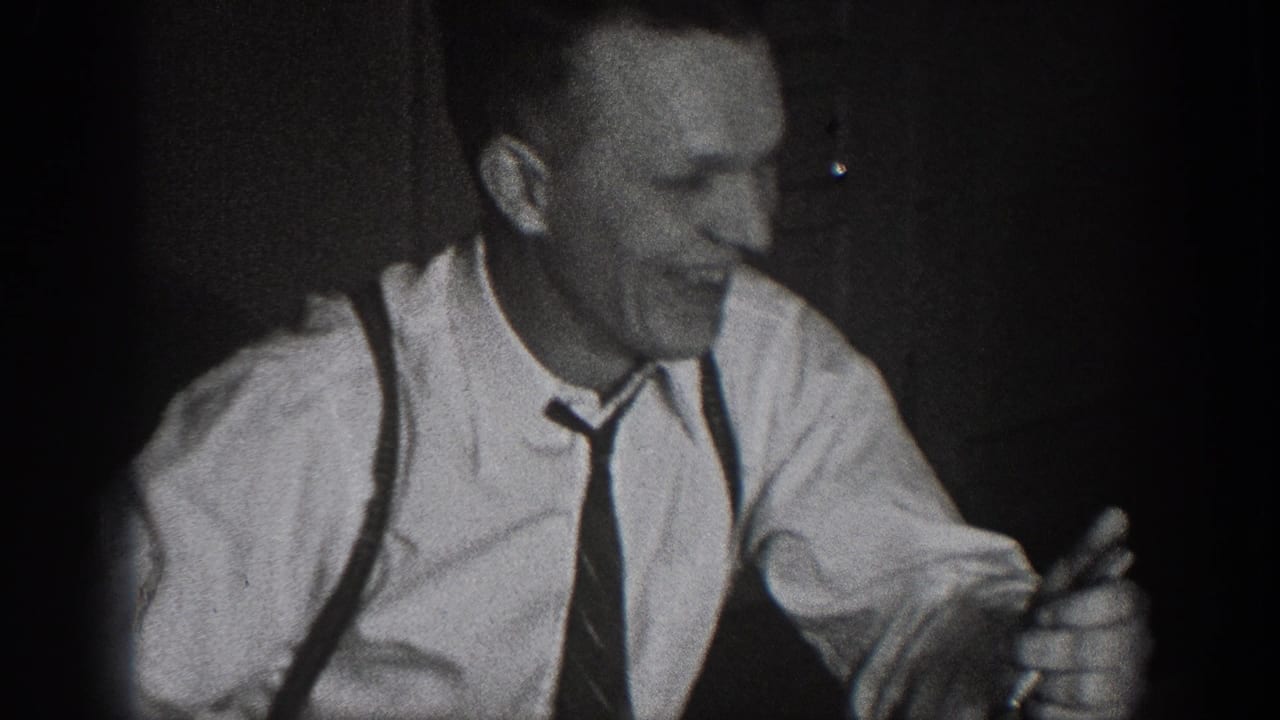 Close-up of man in white dress shirt, suspenders, and dark necktie smiling at dinner; late 1930s dress, Chelan, Washington home movie.
