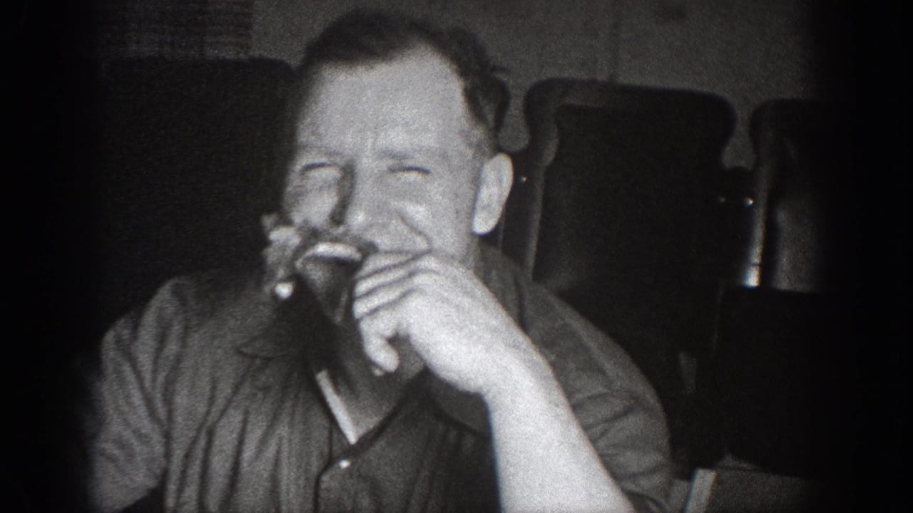 Man in dark collared shirt laughing while eating in a candid home movie moment; circa 1939, attributed to Chelan, Washington.