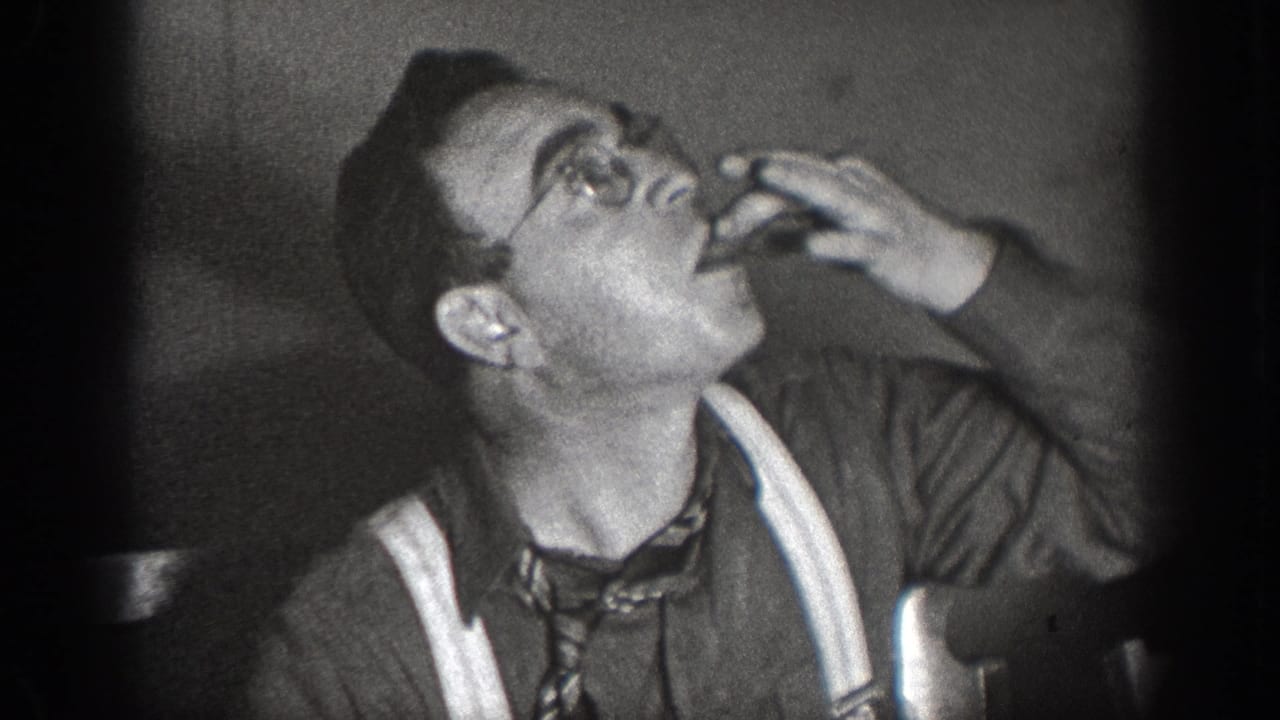 Same man tilts head back with hand at mouth, apparently drinking, against a dark background in black-and-white 8mm footage.