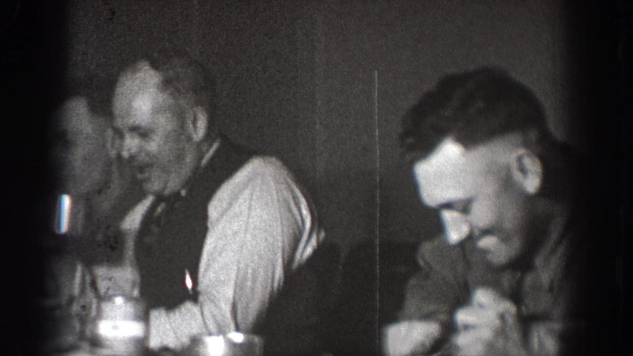 Two adult men at a table with glassware appearing to share a meal or social gathering, Chelan, Washington, circa 1939; 8mm home movie.