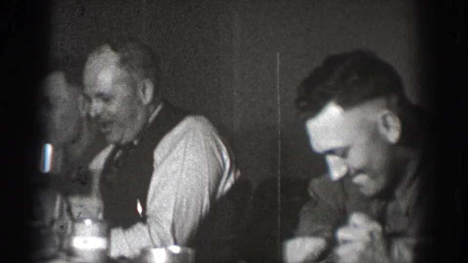 Two adult men at a table with glassware appearing to share a meal or social gathering, Chelan, Washington, circa 1939; 8mm home movie.