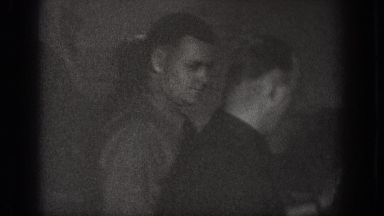 Underexposed close-up of a male figure in a dark indoor setting, Chelan, Washington, circa 1939; 8mm home movie with severe shadow detail loss.