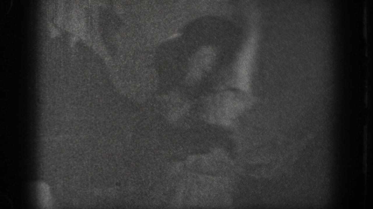 Near-black opening frame from a 1939 Chelan, Washington home movie; a figure is barely discernible in the severely underexposed interior.