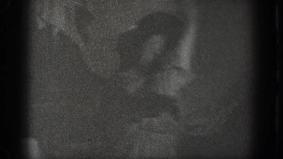 Near-black opening frame from a 1939 Chelan, Washington home movie; a figure is barely discernible in the severely underexposed interior.